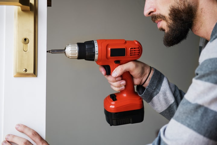 Front door replacement guide - man drilling a screw into a door