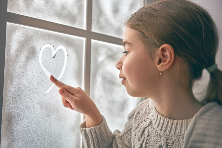 Window maintenance tips - girl drawing heart on the window with her finger